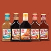 ["Five bottles of Lawry's marinade in different flavors, including Herb &amp; Garlic, Teriyaki, Honey Teriyaki, Steak &amp; Chop, and Signature Steakhouse, are lined up against a brown background."]