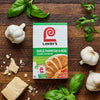 A box of Lawry's Garlic Parmesan &amp; Herb Skillet Sauce Mix is displayed with fresh garlic, basil, parsley, and parmesan cheese on a wooden surface.