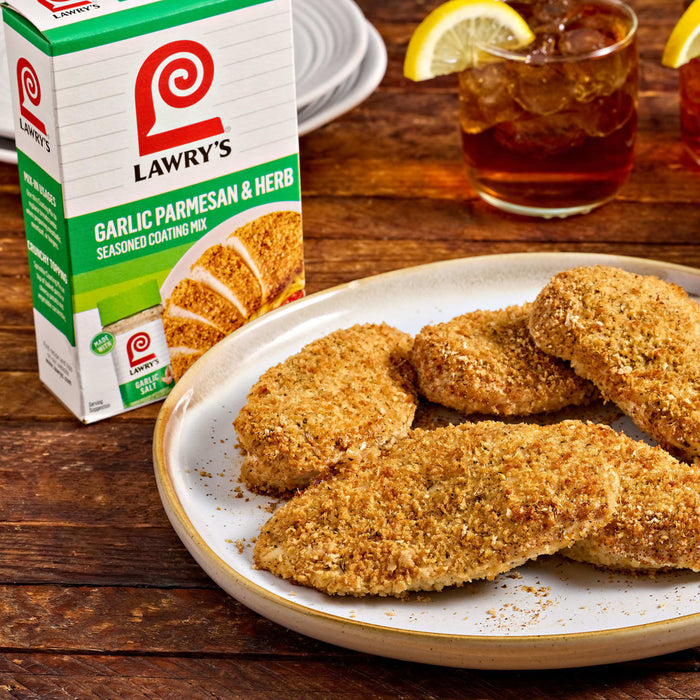 A box of Lawry's Garlic Herb Seasoning Blends sits next to a plate of breaded chicken cutlets, suggesting a delicious meal.