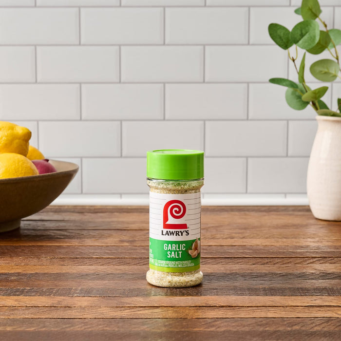 ["A bottle of Lawry's Garlic Salt on a wooden table."]