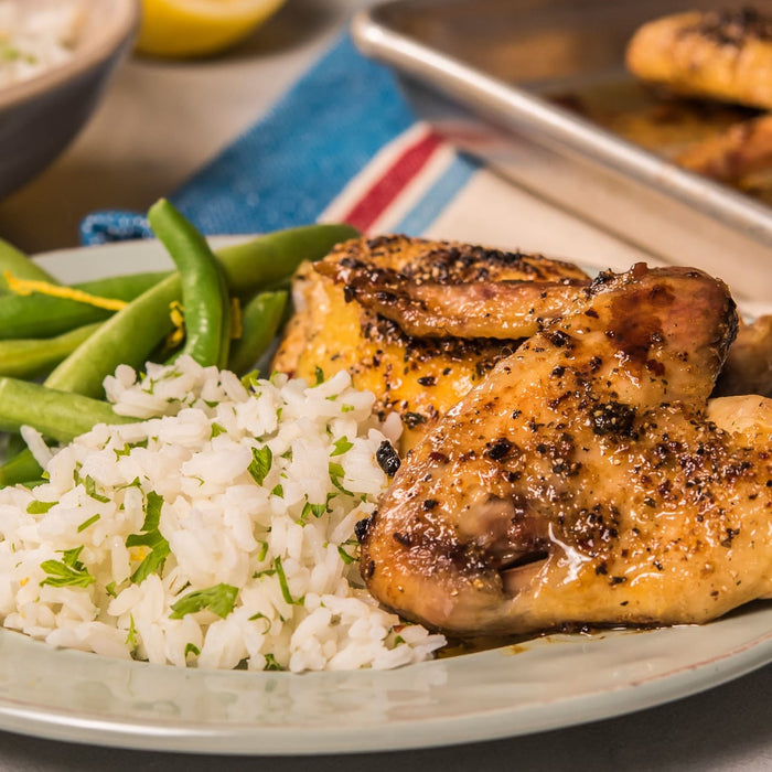 ['A plate of roasted chicken with rice and green beans.']