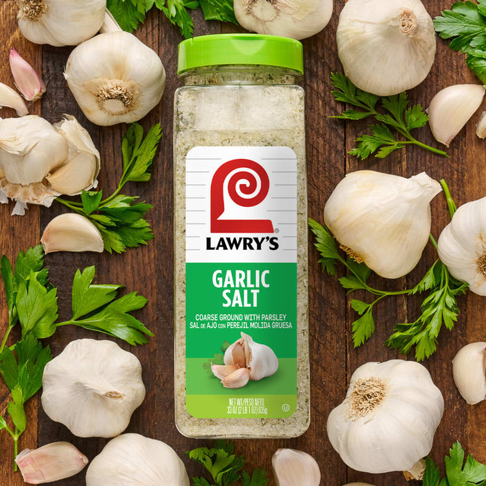 ["A jar of Lawry's Garlic Salt surrounded by garlic and parsley."]