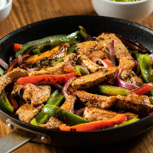 A skillet filled with sizzling fajitas featuring colorful bell peppers, red onions, and seasoned strips of meat.