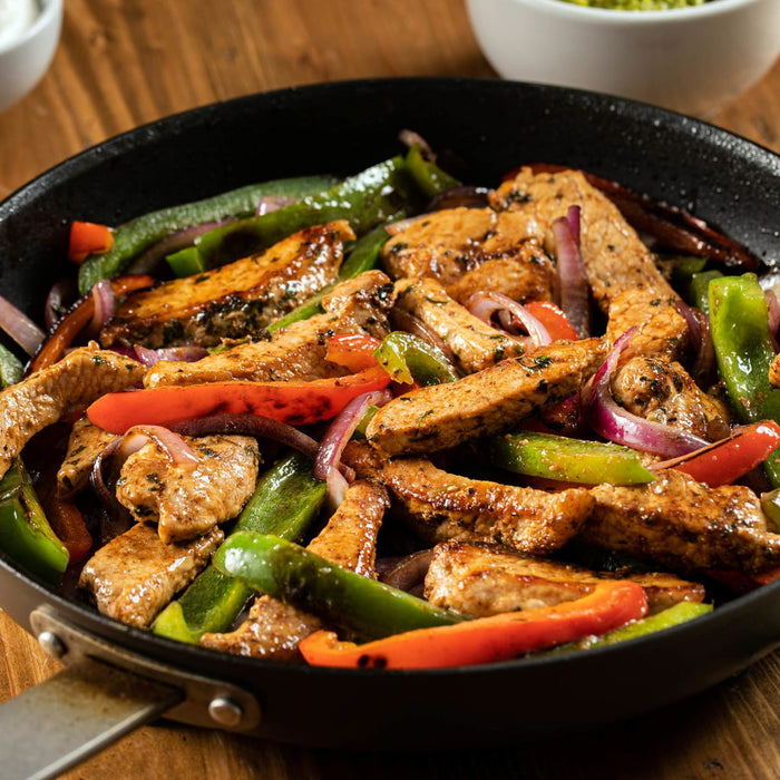 A skillet filled with sizzling fajitas featuring colorful bell peppers, red onions, and seasoned strips of meat.
