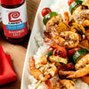 ["A plate of grilled shrimp skewers with vegetables and rice, next to a bottle of Lawry's Seasoned Salt."]