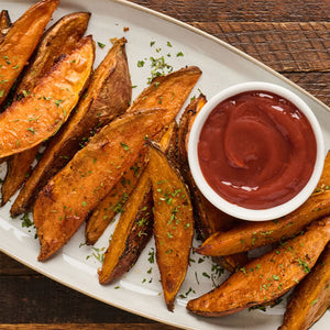 ['A plate of crispy sweet potato fries with a side of ketchup.']