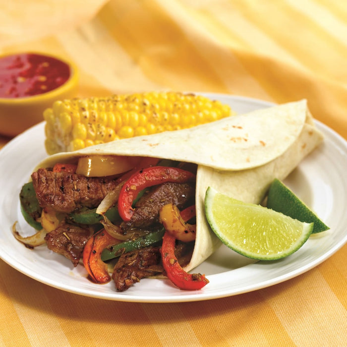 A delicious-looking beef fajita with corn on the cob and a side of salsa is presented on a white plate.
