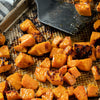 A close-up of a baking sheet with roasted sweet potato cubes.