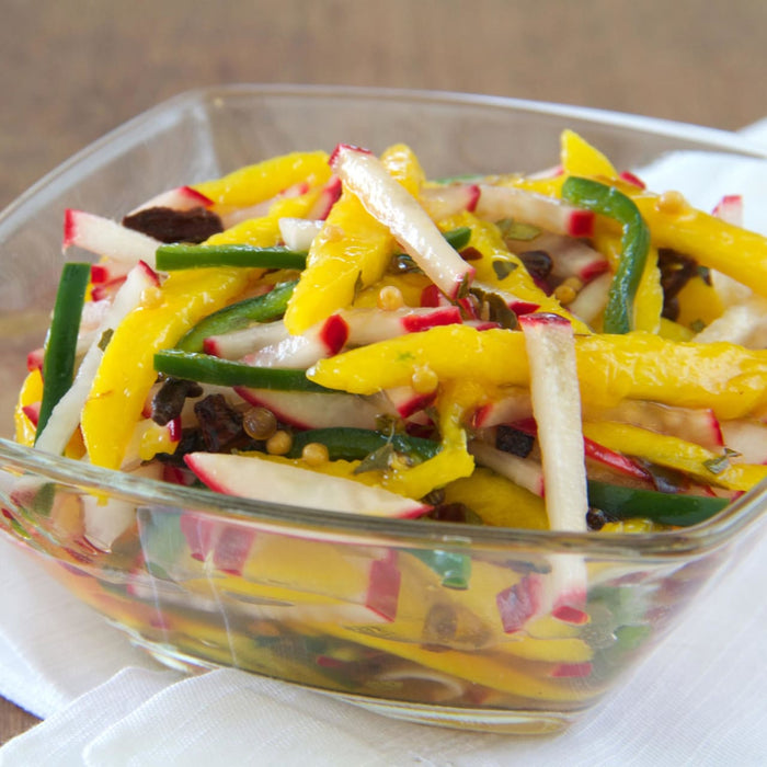 A bowl of fresh salad with yellow peppers, radishes, and green peppers.