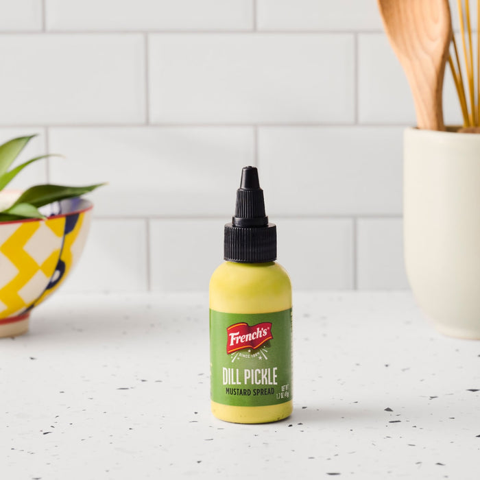 A bottle of French's Dill Pickle Mustard Spread sits on a kitchen counter.