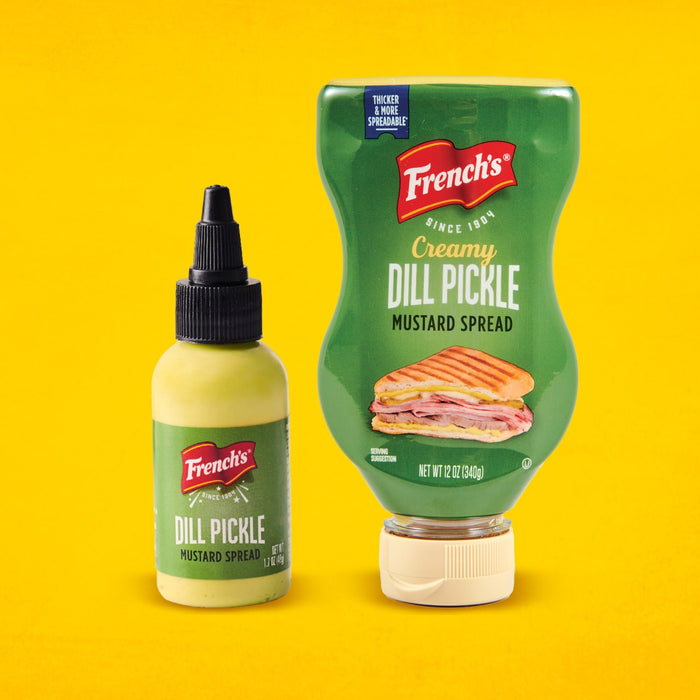 Two bottles of French's Dill Pickle Mustard Spread, one creamy and one regular, are displayed against a yellow background.