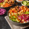 A bowl of rice with salmon carrots cucumbers red cabbage and edamame.