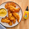 A plate of fried chicken tenders with a bowl of honey mustard and a bottle of French's Honey Mustard Dipping Sauce.