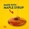 The image shows maple syrup being poured onto a yellow surface, with the text "Made with Maple Syrup" and a red arrow pointing towards the syrup.