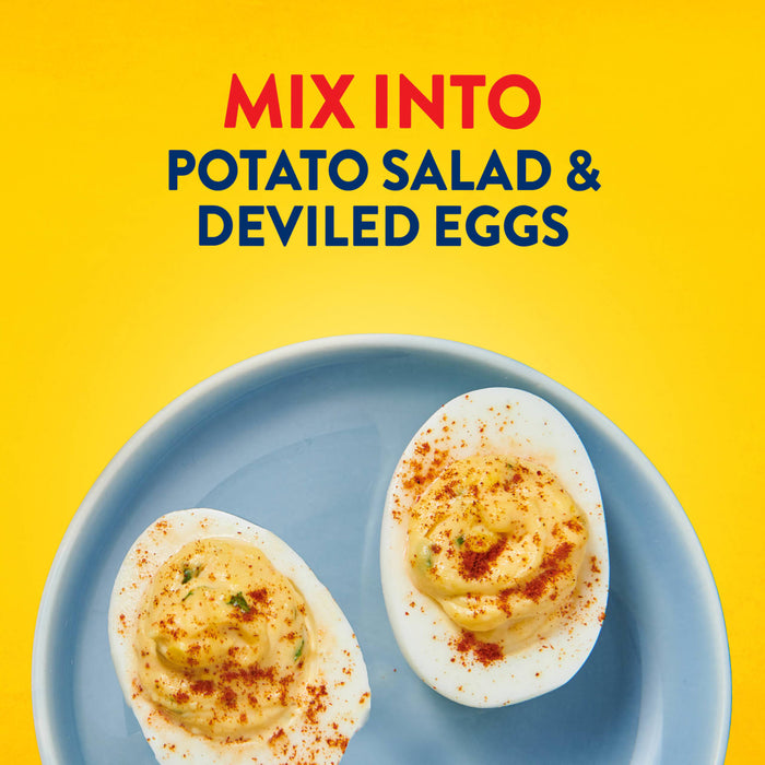 Two deviled eggs topped with paprika sit on a blue plate against a yellow background suggesting a way to use Frenchs Brown Honey Dijon Mustard 12 Oz.