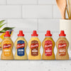 A lineup of five different French's mustard flavors, with the bottle of Frenchs Brown Spicy Brown Mustard 12 Oz in the center, is displayed on a kitchen counter to showcase the brand's variety.