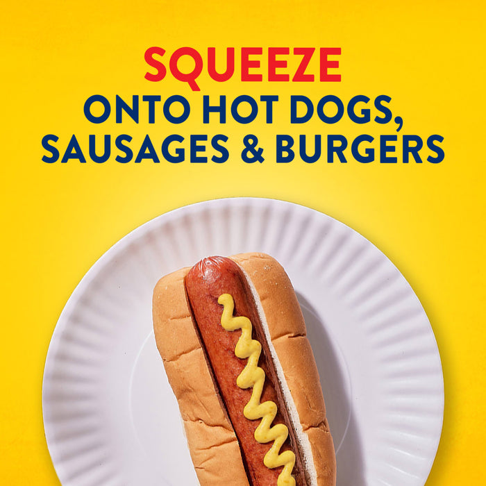A hot dog in a bun on a paper plate is topped with a zigzag of Frenchs Brown Spicy Brown Mustard 12 Oz, with text above that reads, SQUEEZE ONTO HOT DOGS, SAUSAGES &amp; BURGERS.