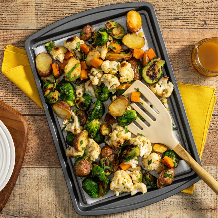 A baking sheet of roasted vegetables like Brussels sprouts and cauliflower is served with a delicious dressing made from Frenchs Beige Dijon Chardonnay Mustard 12 Oz.