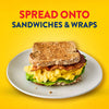 A delicious breakfast sandwich with eggs and bacon on a plate demonstrates a serving suggestion for Frenchs Beige Dijon Chardonnay Mustard 12 Oz, under the text Spread onto sandwiches &amp; wraps.