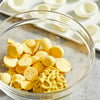 A clear glass bowl contains hard boiled egg yolks and a swirl of Frenchs Yellow Regular Mustard 12 Oz being prepared for deviled eggs.