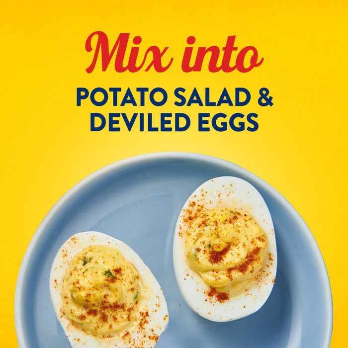 Two deviled eggs sprinkled with paprika on a blue plate illustrate how to mix Frenchs Yellow Regular Mustard 12 Oz into classic side dishes.