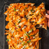 ['A close-up of a buffalo chicken pizza with melted cheese and green onions.']