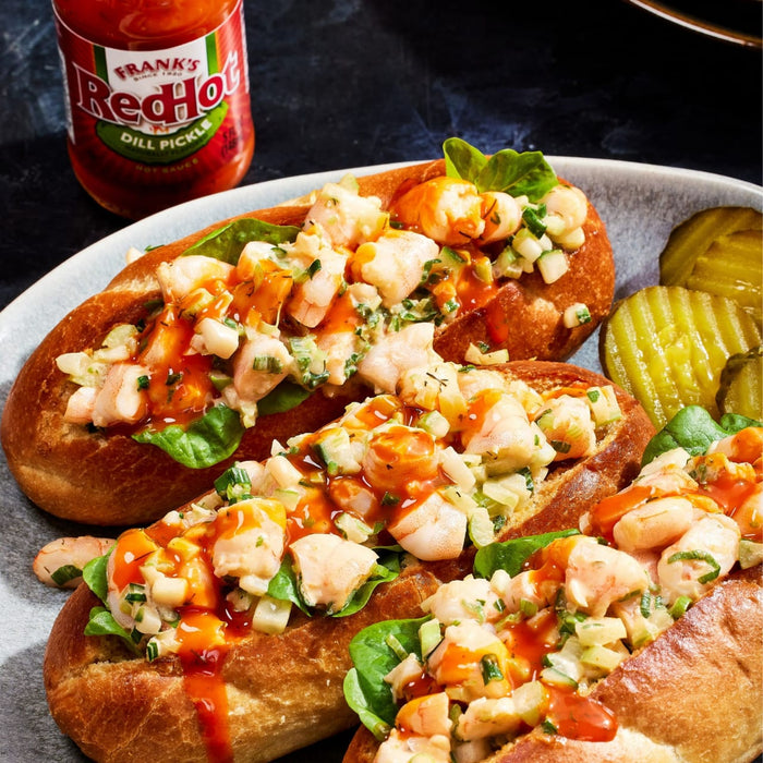 ["Three shrimp rolls topped with Frank's RedHot sauce and garnished with green onions and spinach."]