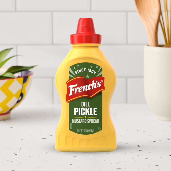A yellow squeeze bottle of Frenchs Dill Pickle Sandwich Spread Regular Inverted Squeeze Bottle Rp 12 Oz is set on a white kitchen countertop.