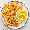 A top-down view of a plate of crispy french fries served with a small bowl of Frenchs Dill Pickle Sandwich Spread Regular Inverted Squeeze Bottle Rp 12 Oz for dipping.