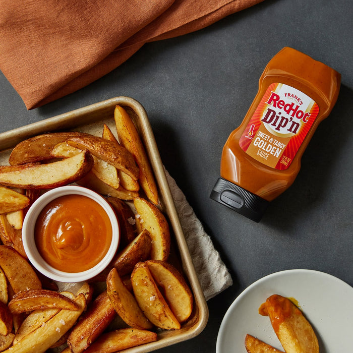 ["A bowl of dipping sauce next to a plate of potato wedges and a bottle of Frank's RedHot Dip'n Golden Sauce."]