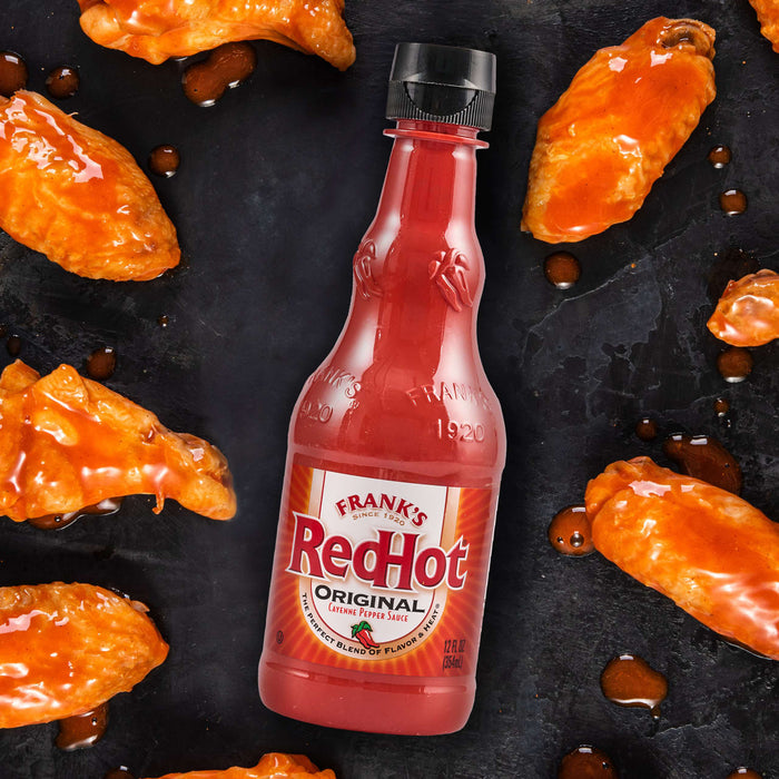 A bottle of Frank's RedHot sauce is surrounded by delicious looking chicken wings.