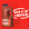 A large jug of Franks Red Hot Mango Habanero Wing Hot Sauce Regular 64 Oz is displayed against a vibrant red background with the bold white text Kick It Up A Notch inside a brushstroke circle.