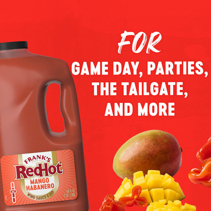 A large jug of Franks Red Hot Mango Habanero Wing Hot Sauce Regular 64 Oz is displayed against a vibrant red background alongside fresh mango and habanero peppers to highlight its use for game day and parties.