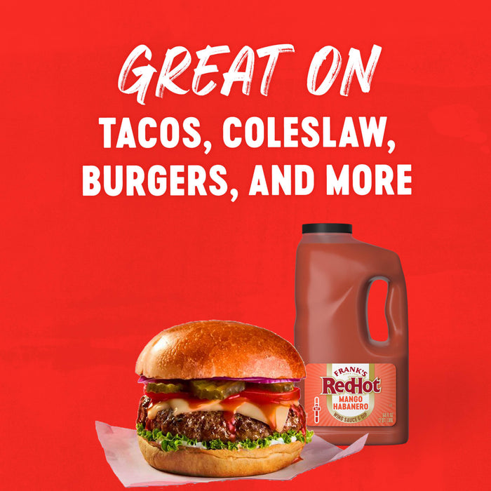 A large bottle of Franks Red Hot Mango Habanero Wing Hot Sauce Regular 64 Oz sits next to a loaded cheeseburger on a red background with text suggesting it is great on tacos, coleslaw, and more.