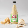 A bottle of Frank's RedHot Garlic Parmesan sauce is displayed with parmesan cheese and garlic cloves.
