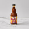 A bottle of Frank's RedHot Wings General Tso Sauce sits on a marble surface.