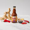 A bottle of Frank's RedHot Wings General Tso sauce is displayed with ginger and red chili peppers.