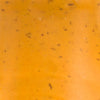 A close-up of a smooth orange surface with small black specks.