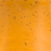 A close-up of a smooth orange surface with small black specks.