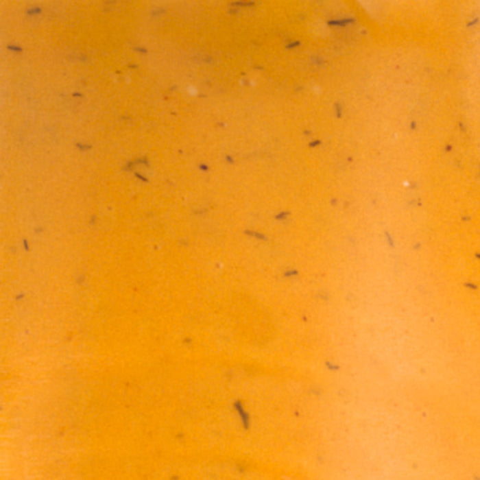 A close-up of a smooth orange surface with small black specks.