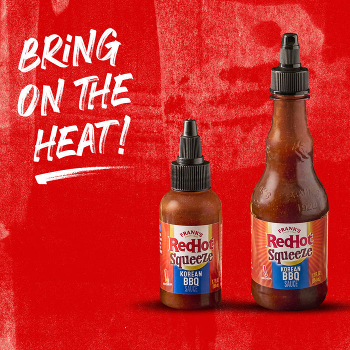 Two bottles of Franks RedHot Squeeze Korean BBQ sauce on a red background.