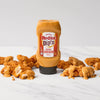 A bottle of Franks RedHot Dipn Secret Chicken Sauce is surrounded by fried chicken tenders drizzled with the same sauce.