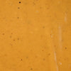 A close-up shot of a smooth orange-colored sauce with small specks of herbs and spices.