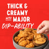 A hand dips a crispy chicken nugget into a bowl of thick creamy sauce highlighting its major dip-ability.