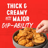 A hand dips a crispy chicken nugget into a bowl of thick creamy sauce highlighting its major dip-ability.
