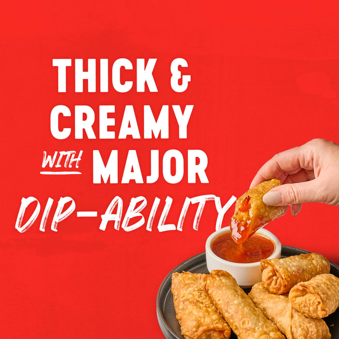 A hand dips a golden-brown egg roll into a bowl of sauce highlighting the products thick and creamy texture with major dip-ability.