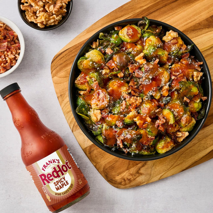A bowl of Brussels sprouts with bacon and walnuts is presented with a bottle of Frank's RedHot sauce.
