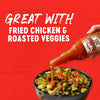 A bottle of Red Hot sauce is being poured over a bowl of roasted vegetables, highlighting the product's versatility.