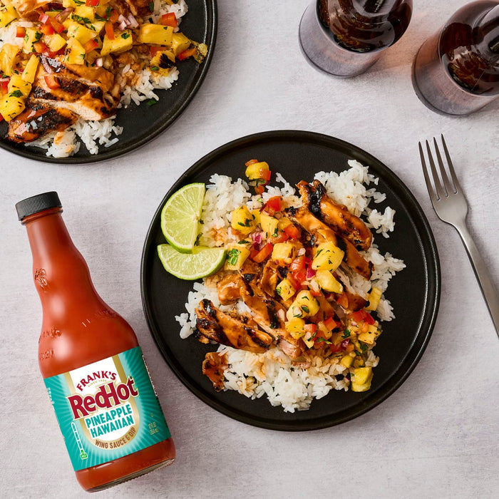 A plate of grilled chicken and rice topped with mango salsa and a bottle of Frank's RedHot Sweet Chili Sauce.