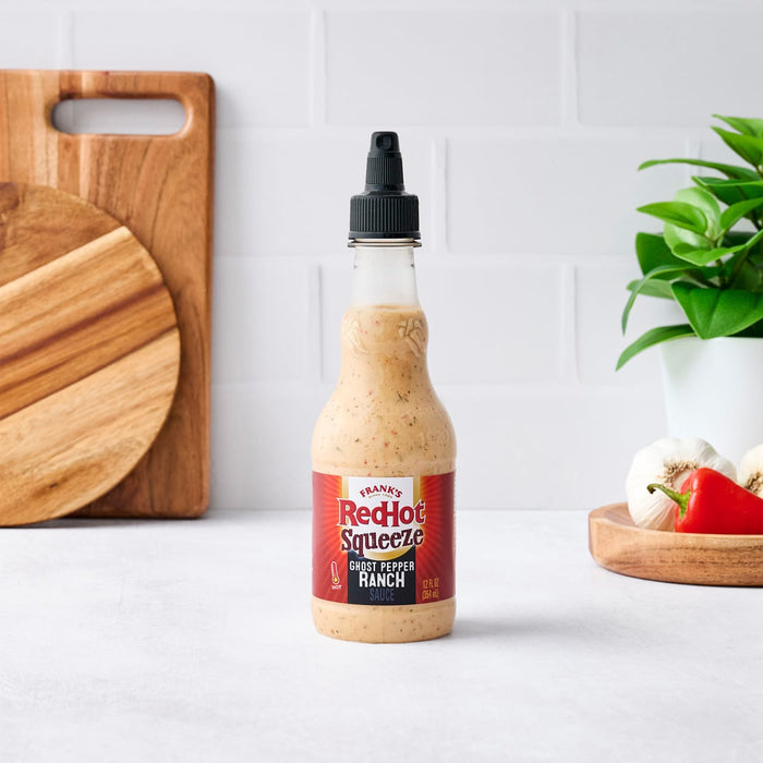 A bottle of Budlong Sweet Heat Sauce sits on a counter with kitchen accessories.